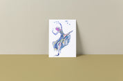 Mockup image of a 6 by 9 inch art print of a ballerina. She is wearing a blue gown with her arms in the air reaching towards the stars